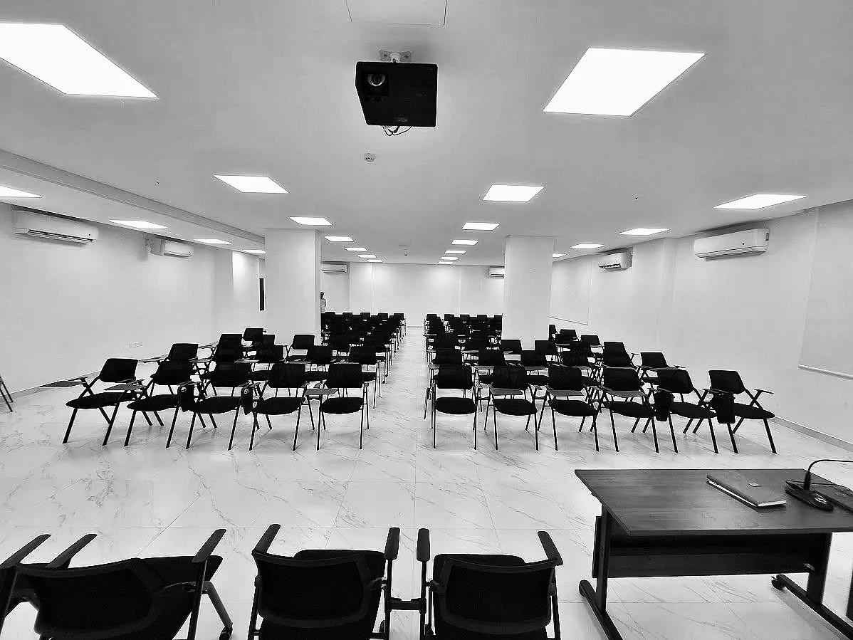 قاعة فعاليات العدلية فارغة بصفوف جلوس ومكتب للمتحدّث